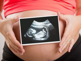 femme tenant une échographie devant son ventre