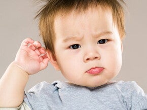 bébé étonné qui se touche l'oreille