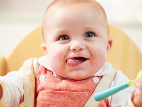 bebe dans chaise haute avec sa cuillère