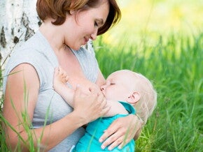 maman allaitant son bebe dans l'herbe