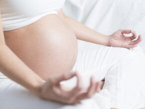 Ventre de femme enceinte en position de yoga.