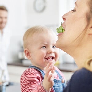 Bébé qui donne à manger à sa maman avec papa en arrière-plan