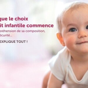 Bébé rampant dans une tenue blanche, fond flou.