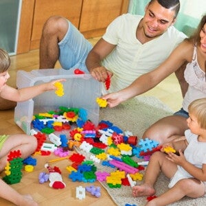 Papa et maman jouent aux jeux de construction avec leurs deux enfants à même le sol