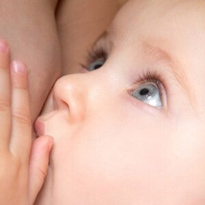 bebe aux yeux bleu tetant le sein de sa maman