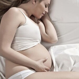 femme enceinte allongee sur le cote une main sur le ventre