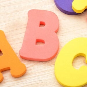 jeu de lettres colorés en mousse posé sur un parquet