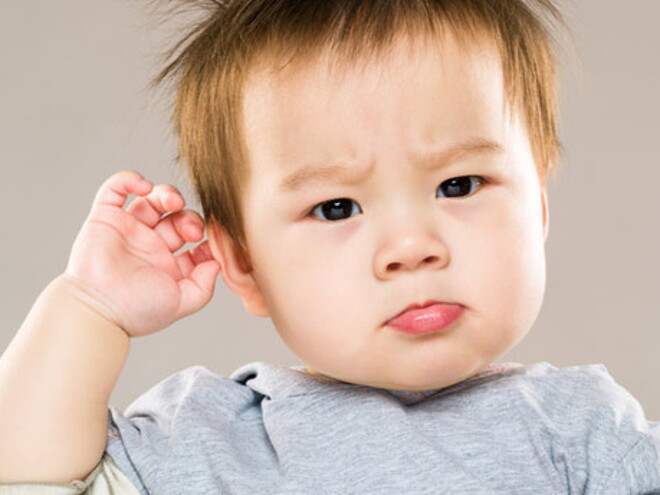 bébé étonné qui se touche l'oreille