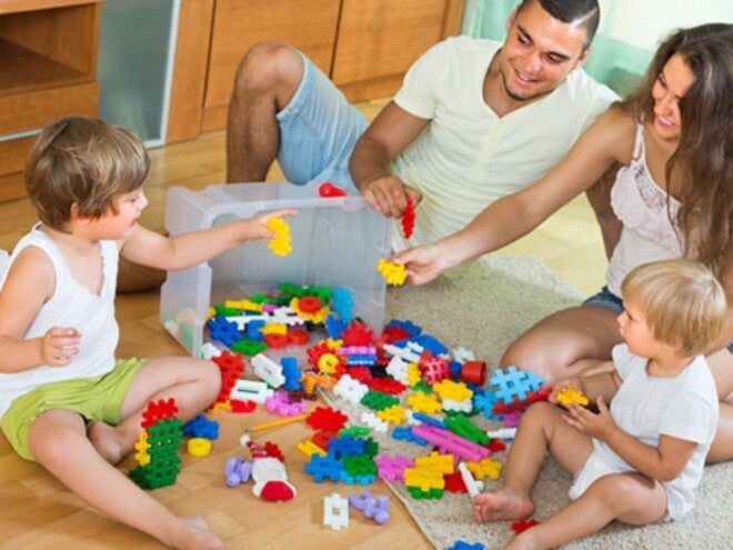 Papa et maman jouent aux jeux de construction avec leurs deux enfants à même le sol Papa et maman jouent aux jeux de construction avec leurs deux enfants à même le sol
