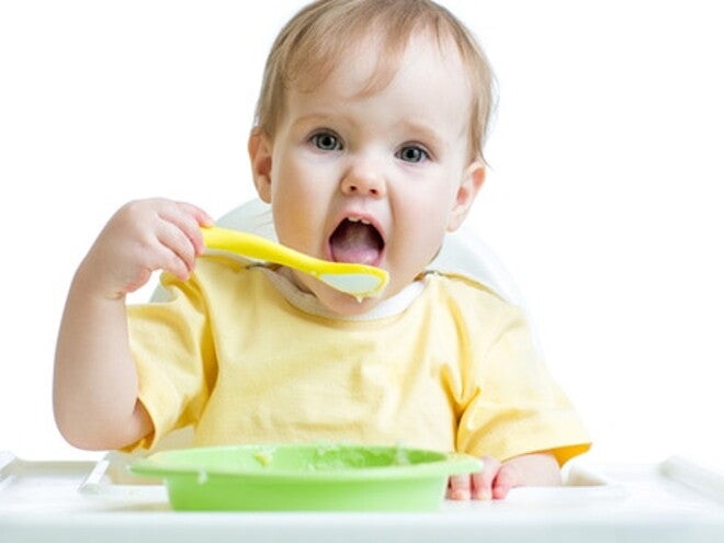 bébé porte une cuillère à sa bouche