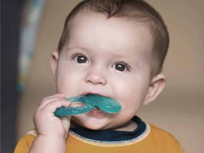 bebe qui porte un jouet a sa bouche