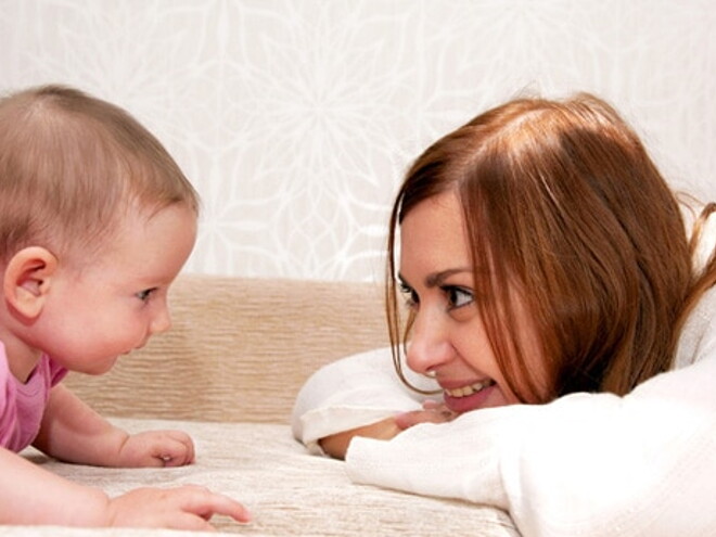 Maman est accroupie face à bébé qui rampe et sourit en le regardant Maman est accroupie face à bébé qui rampe et sourit en le regardant