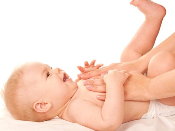 mains qui massent le ventre d'un bebe