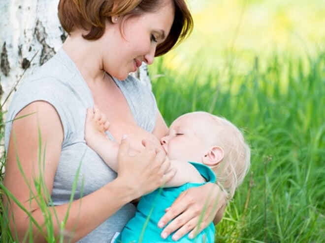 maman allaitant son bebe dans l'herbe